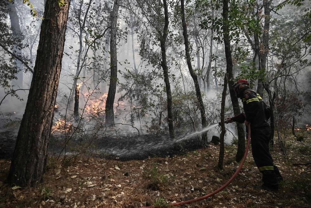 A firefighter sprays water in an attempt to extinguish a wildfire and stop it spreading in the Dadia-Lefkimi-Soufli Forest National Park, near Alexandroupoli, northern Greece on Sept 2. (Photo by Sakis MITROLIDIS / AFP)