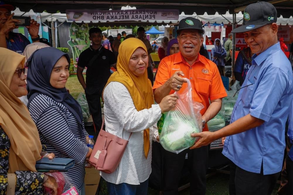 Agriculture and Food Security Minister Datuk Seri Mohamad Sabu (second from the right) handing over daily needs to buyers at the 2023 National-level Mega Agro Madani Sales Carnival in Dataran Sejarah, Ayer Keroh. - BERNAMA PIX