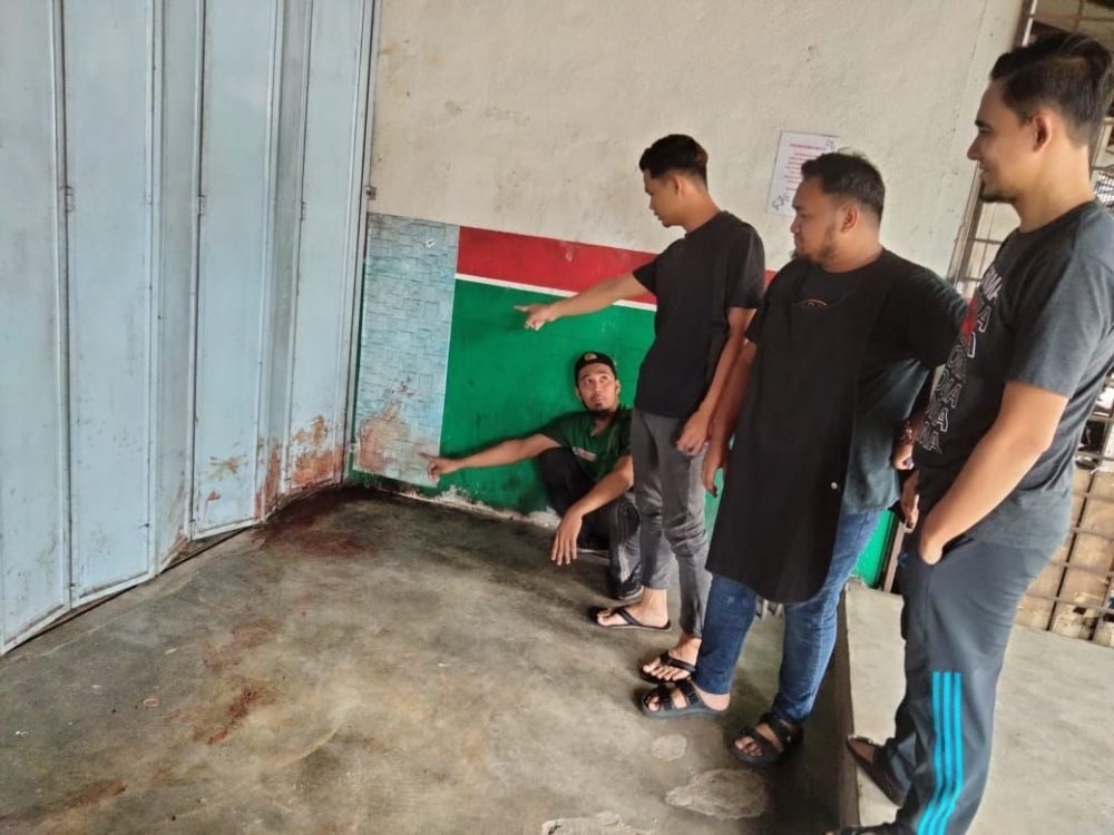 Zahid (sitting) who was a witness to the incident pointing at the bloodstains at the scene.