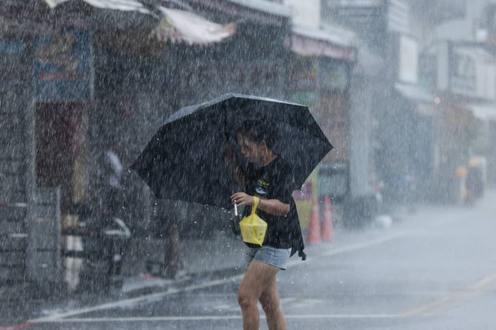 A woman walks with an umbrella during heavy rain near Su-ao port in Yilan as Typhoon Haikui makes landfall in eastern Taiwan on Sept 3, 2023. - (Photo by I-Hwa Cheng / AFP)