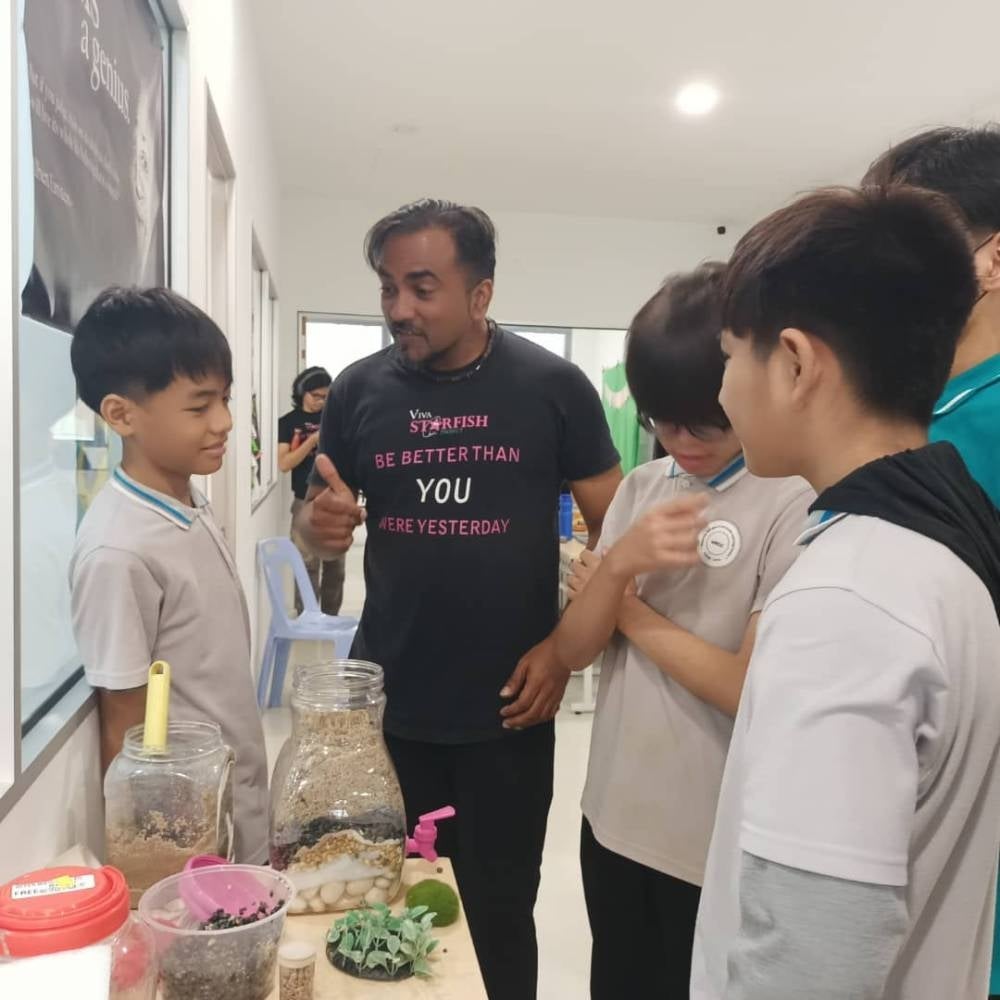 Jerryson (centre) assisting children on ways to distill water, a project that will be carried out at an Orang Asli village