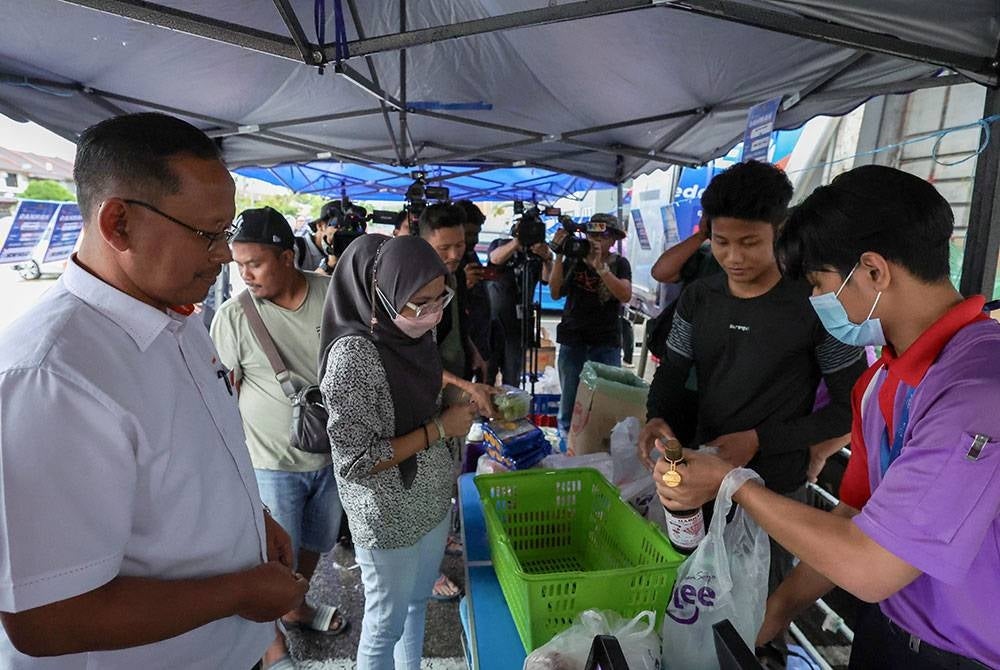 Suhaizan (left) meeting with the local community present at the Rahmah Sales Programme in the Perling People's Housing Project (PPR) along Jalan Rawa. - BERNAMA PIX