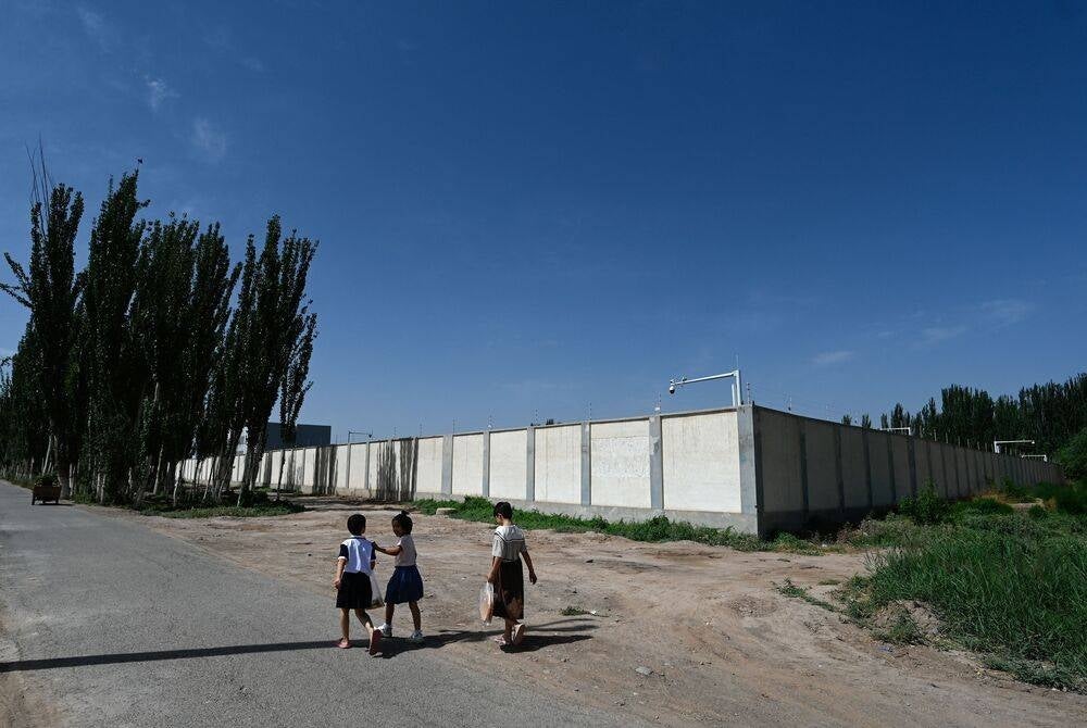 TOPSHOT - This picture taken on July 15 shows children walking past a disused detention centre near Kashgar in China's northwestern Xinjiang region. (Photo by Pedro PARDO / AFP) 