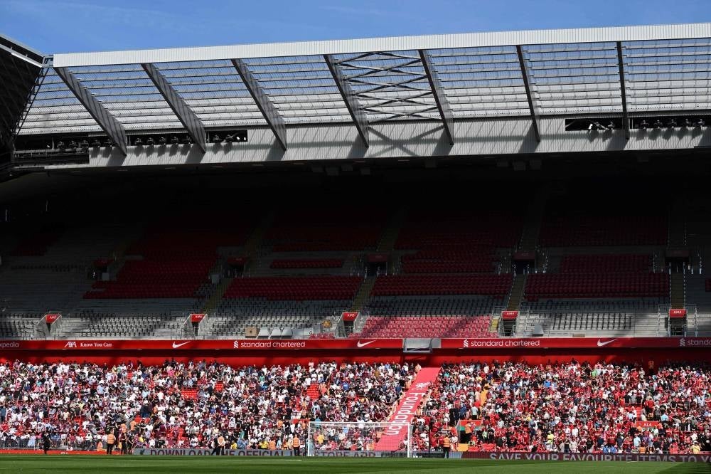 Supporters sit on the down part of the stadium as the up part of the stands are under construction. - Photo by Paul Ellis / AFP