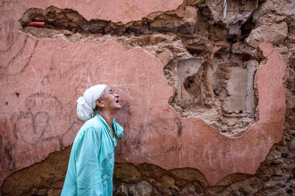 A woman reacts standing infront of her earthquake-damaged house in the old city in Marrakesh on September 9, 2023. (Photo by FADEL SENNA / AFP)