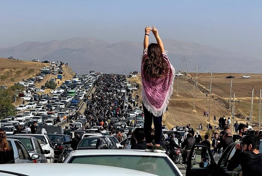 (FILES) This UGC image posted on Twitter reportedly on Oct 26, 2022 shows an unveiled woman standing on top of a vehicle as thousands make their way towards Aichi cemetery in Saqez, Mahsa Amini's home town in the western Iranian province of Kurdistan, to mark 40 days since her death, defying heightened security measures as part of a bloody crackdown on women-led protests. (Photo by UGC / AFP)