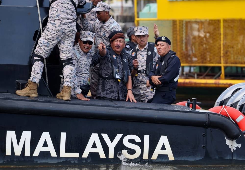 Immigration director-general Datuk Ruslin Jusoh (two, left) with Kelantan police chief Datuk Muhammad Zaki Harun (left) observing the country's borders in a boat at Sungai Golok, today. - Photo by Bernama 