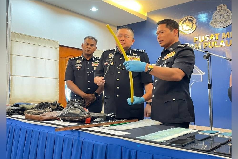 Kok Chin (centre) showing some of the items seized from the suspect.