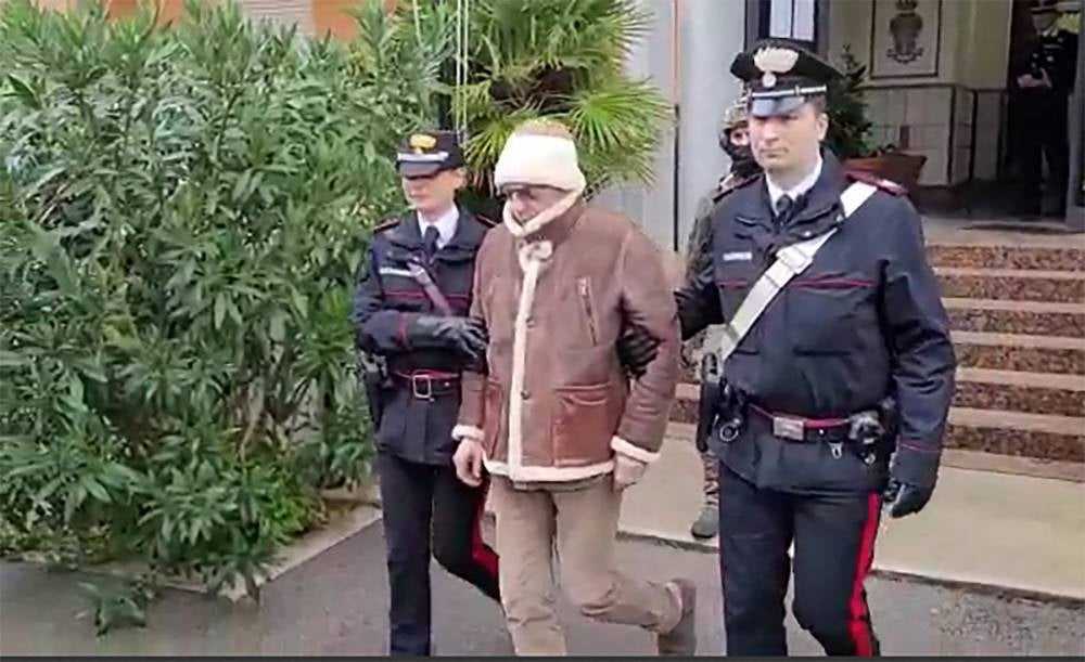 This handout video grab taken and released by the Italian Carabinieri Press Office on January 16, 2023 shows the transfer of Italy's top wanted mafia boss, Matteo Messina Denaro (C) from the Carabinieri police station of San Lorenzo in Palermo, to an undisclosed location, following his arrest in his native Sicily on January 16, 2023 after 30 years on the run. - FILE PIX by AFP