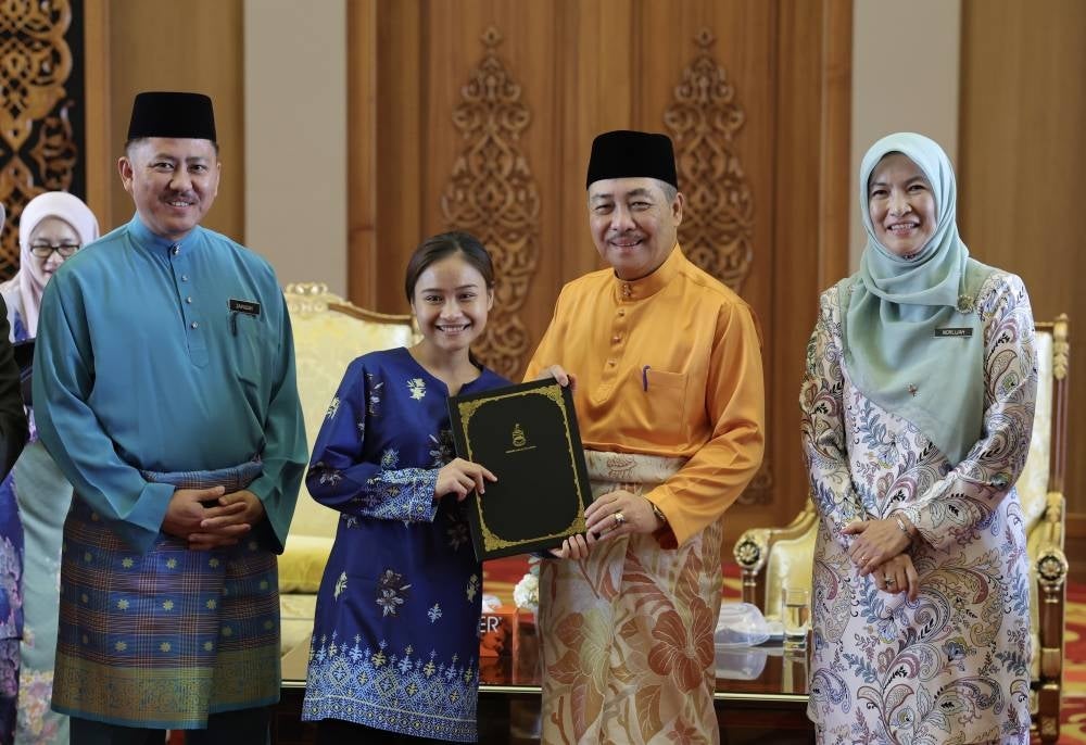Sabah Chief Minister Datuk Seri Hajiji Noor handing the excellent scholarship to a student Arnie Jaliusih from Kampung Sinansak Kiulu at Menara Kinabalu - BERNAMA PIX