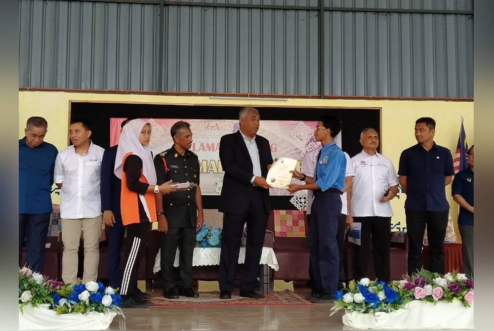 Khairudin (centre) presenting certificates to SMK Malim Nawar students at the 30 Laptops Handover Ceremony by Maxis Berhad at SMK Malim Nawar today.