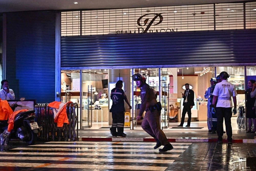 Police officers and rescue workers stand outside Siam Paragon shopping centre in Bangkok on Oct 3, following a shooting incident in the mall. - Photo by AFP