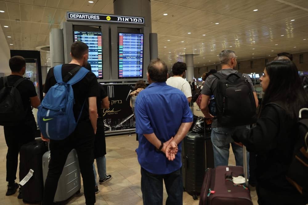 Passengers look at a departure board at Ben Gurion Airport near Tel Aviv, Israel, on Oct 7 as flights are cancelled because of the Hamas surprise attacks. - Photo by AFP