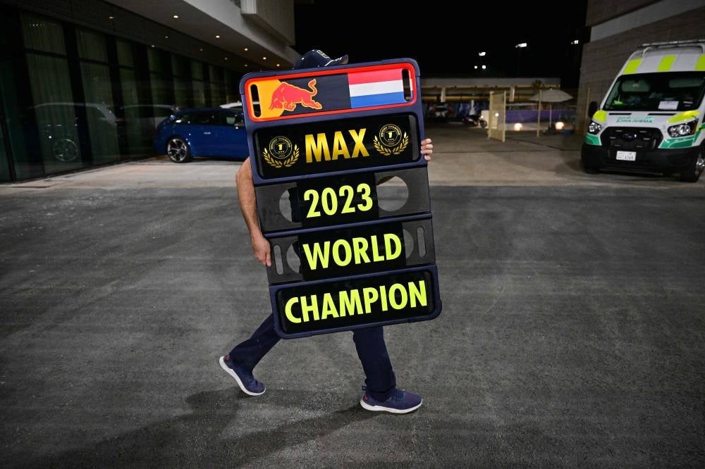 A Red Bull Racing team member carries a sign bearing the name of 2023 world champion Max Verstappen after the sprint race ahead of the Qatari Formula One Grand Prix at the Lusail International Circuit on October 7, 2023. - Photo by AFP