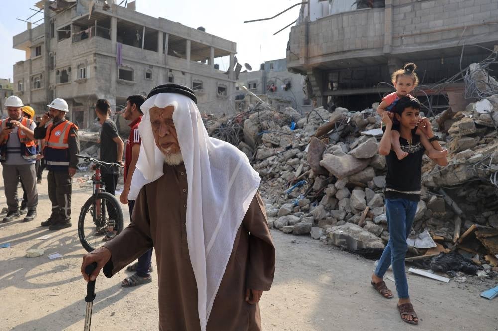 Civilians and rescue teams gather outside a destroyed building, following Israeli airstrikes on Rafah in the southern Gaza Strip, on Oct. - Photo by AFP