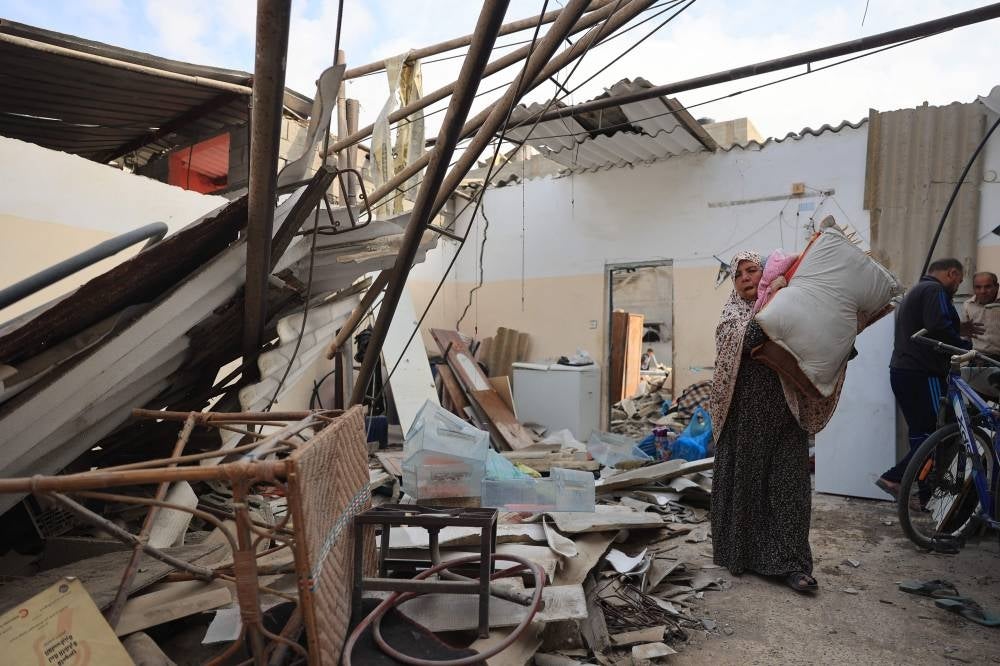 A Palestinian woman salvages items from her home which was damaged
during Israeli airstrikes on Rafah in the southern Gaza Strip, on Oct 8. - Photo by AFP