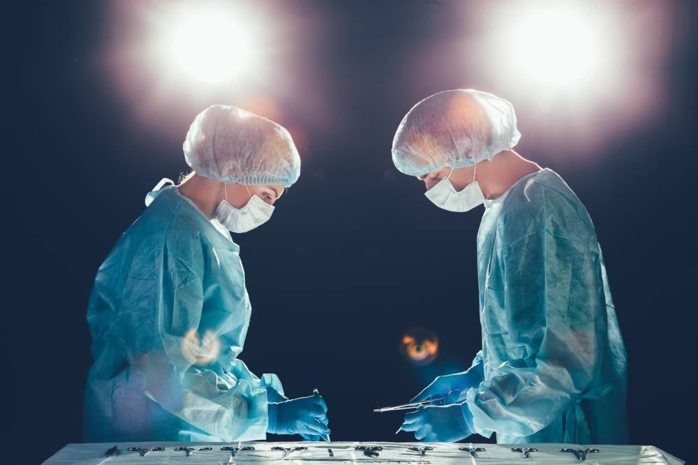 Medical team in hospital performing operation. Group of surgeon at work in operating theatre room. healthcare Bright light in the frame artistic effect