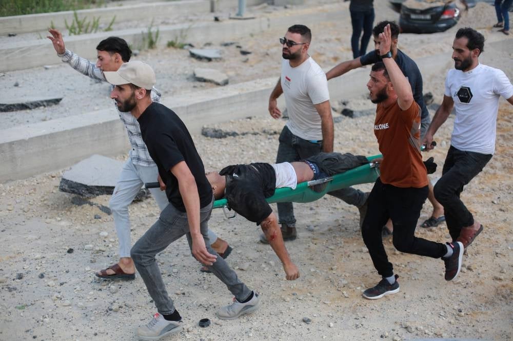 Palestinian men carry a wounded youth following an Israeli air strike at the Erez crossing between Israel and the northern Gaza Strip on October 7, 2023. Photo by Bashar Taleb/AFP FILE PIX