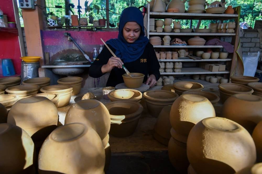 Nur Syazwani Izyan Jefridin, the owner of Belipot Craft Ceramic, diligently works on assembling parts of a clay kiln heater in Kampung Bunut Payong on Sept 22, 2023. (BERNAMA PHOTO) 