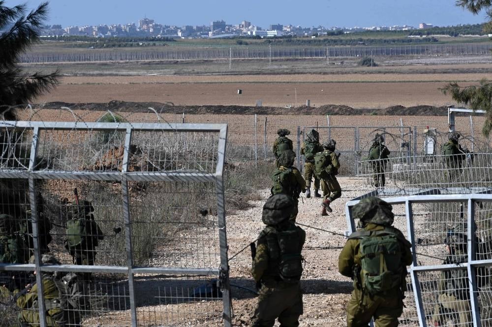Israeli soldiers patrol a border fence gate with the Gaza Strip on October 15, 2023. - Photo by AFP