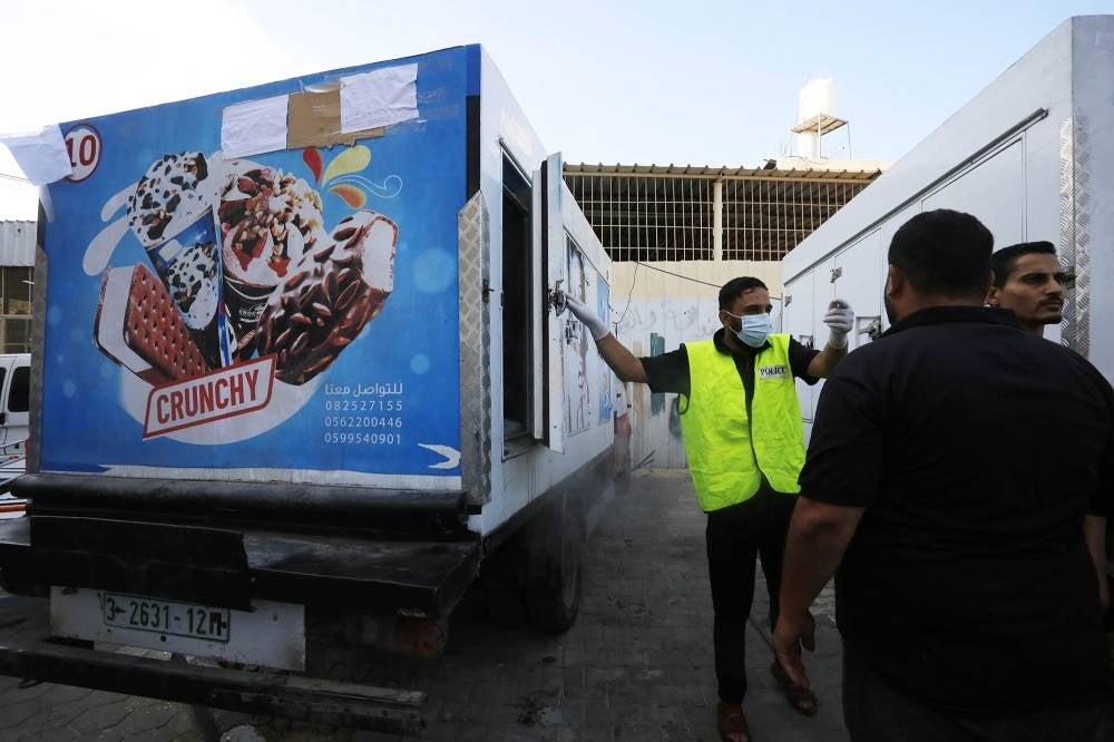 A police officer places dead bodies in ice cream refrigerators due to the insufficiency of the hospital morgues at the Suheda al-Aqsa Hospital (Al-Aqsa Martyrs Hospital) - PIX by ANADOLU AGENCY / REUTERS 
