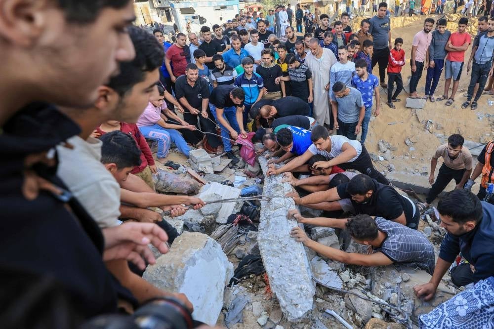 Palestinians look for survivors trapped under the rubble of a building destroyed in an Israeli airstrike in Khan Yunis in the southern of Gaza Strip on October 16, 2023 - AFP