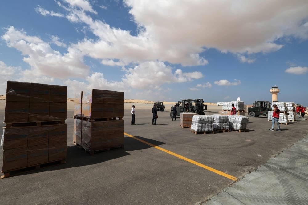 Staff members unload aid for the Palestinian Gaza Strip transported on an Emirates cargo plane on the tarmac of Egypt's el-Arish airport in the north Sinai Peninsula on October 19, 2023. - Photo by AFP