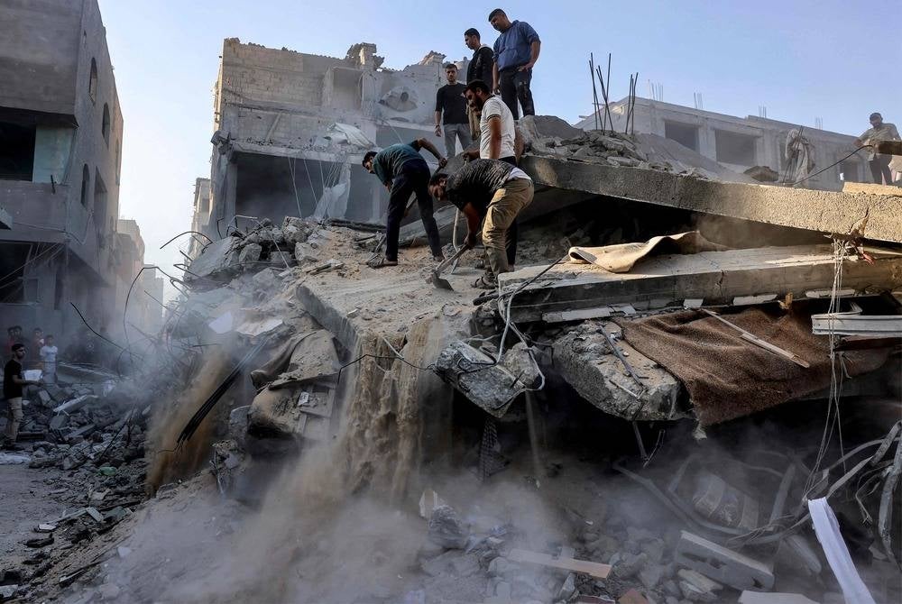 People dig and search through the rubble of a destroyed building following Israeli bombardment in Rafah in the southern of Gaza Strip on Oct 19. (Photo by Mohammed ABED / AFP)