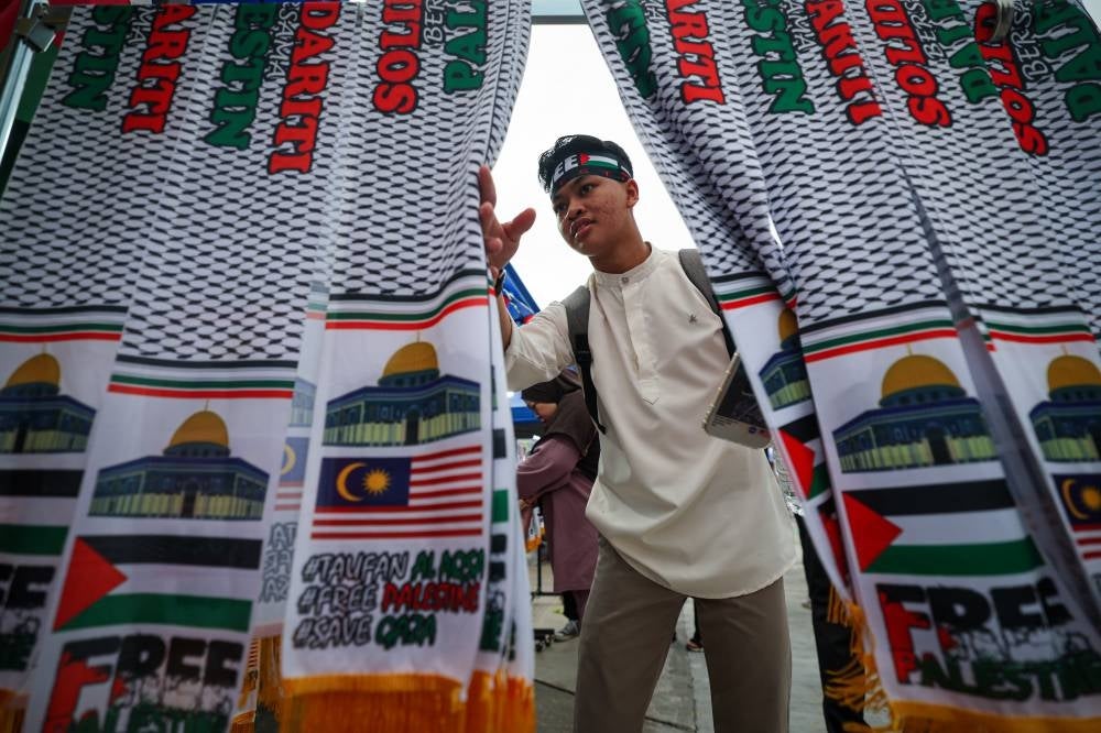 Flags and banner reflecting the Malaysian-Palestinian support being sold in the grounds of Axiata Arena Bukit Jalil during the Malaysia Stands with Palestine gathering on Oct 24. (PHOTO BY BERNAMA)