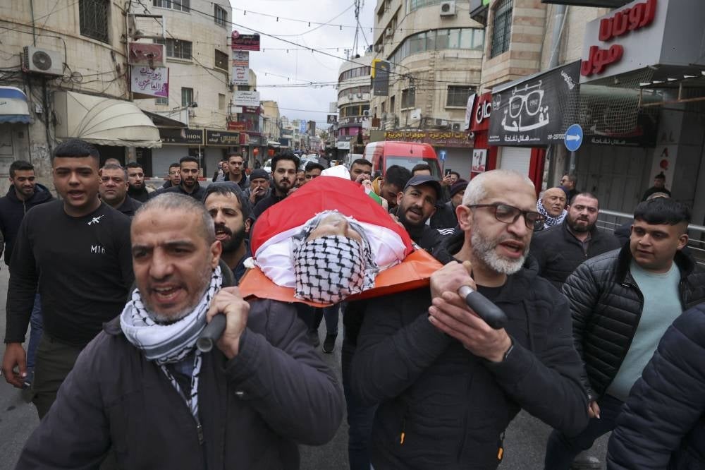 Palestinian residents carry the body of a man who was killed during an Israeli military raid in the West Bank. - Photo by AFP