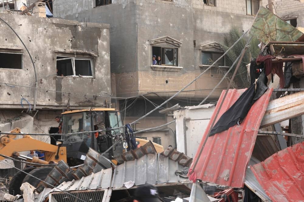 Palestinian women stand at a window as they watch a bulldozer clearing debris following the ongoing Israeli bombardment of Khan Yunis and other areas of the Gaza Strip on October 27, 2023. Photo by Mahmud Hams/AFP