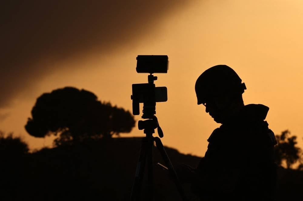 A member of the media stands behind his camera at a spot overlooking the Gaza Strip in the southern Israeli city of Sderot. Photo by Jack Guez/AFP