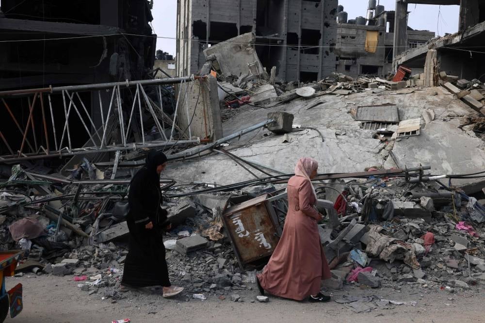  Women walk past a destroyed building in the aftermath of Israeli bombing in Rafah in the southern Gaza Strip on October 28, 2023 - AFP 