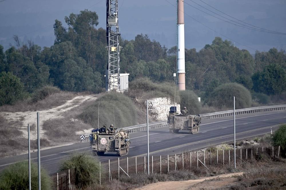 Israeli soldiers ride armoured vehicles near the southern Israeli city of Sderot on October 28, 2023, amid the ongoing war between Israel and the Palestinian group Hamas. Battles raged in Gaza on October 28, 2023, as Israel's army said it expanded ground operations after intensifying its bombardment of the Palestinian territory three weeks after the deadliest attack in the country's history. (Photo by Aris MESSINIS / AFP)