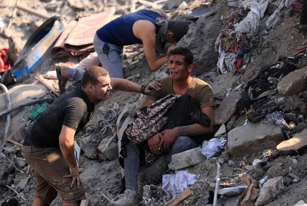 A man reacts as he holds the remains of his mother wrapped in a blanket amid the rubble of building destroyed in an Israeli strike on the Bureij refugee camp in the central Gaza Strip on Nov 2, 2023, as battles between Israel and the Palestinian Hamas movement continue. (Photo by MAHMUD HAMS / AFP)