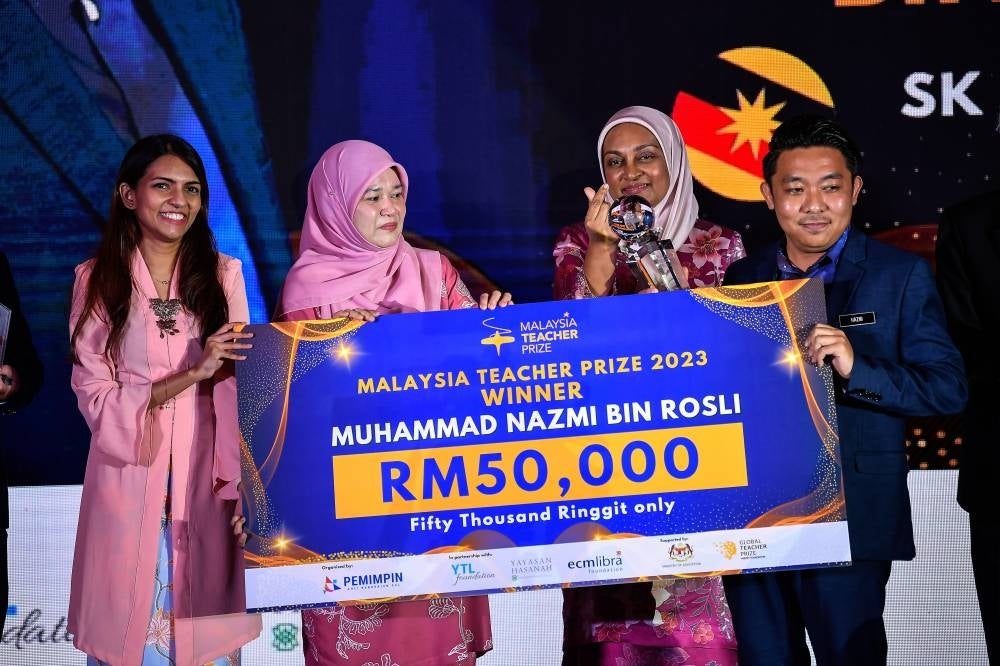Education Minister Fadhlina Sidek (second from the left) giving the award and replica mock cheque to the Malaysia Teach Prize winner Muhammad Nazmi Rosli (right) during the 2023 Malaysia Teacher Prize Award at the Sime Darby Convention Centre - BERNAMA PIX