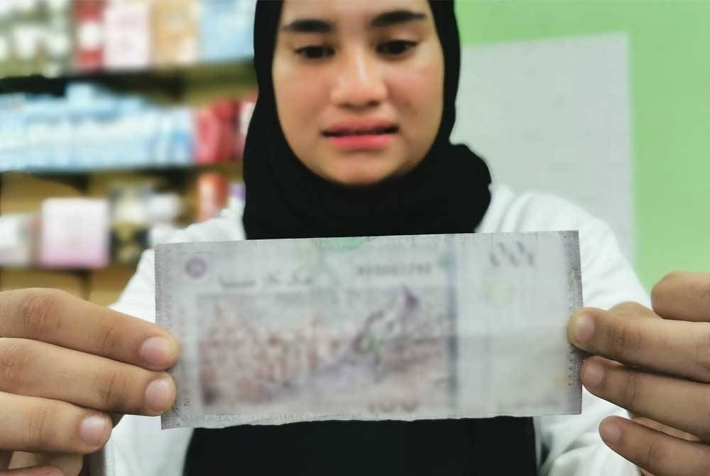 Nurul Safizal showing the counterfeit RM100 bill received