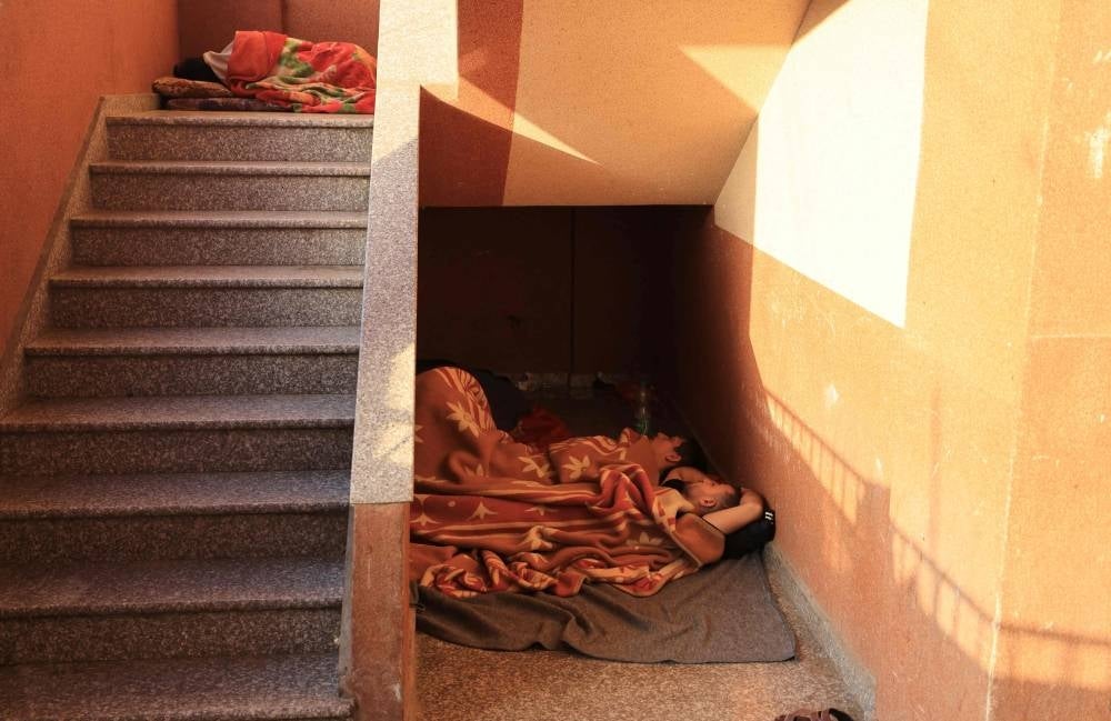 Internally displaced Palestinians from the Gaza Strip, looking for safety sleep in the stairwell as others are camped in the grounds of the al-Nasser hospital in Khan Yunis in the southern Gaza Strip on November 9, 2023 - AFP 
