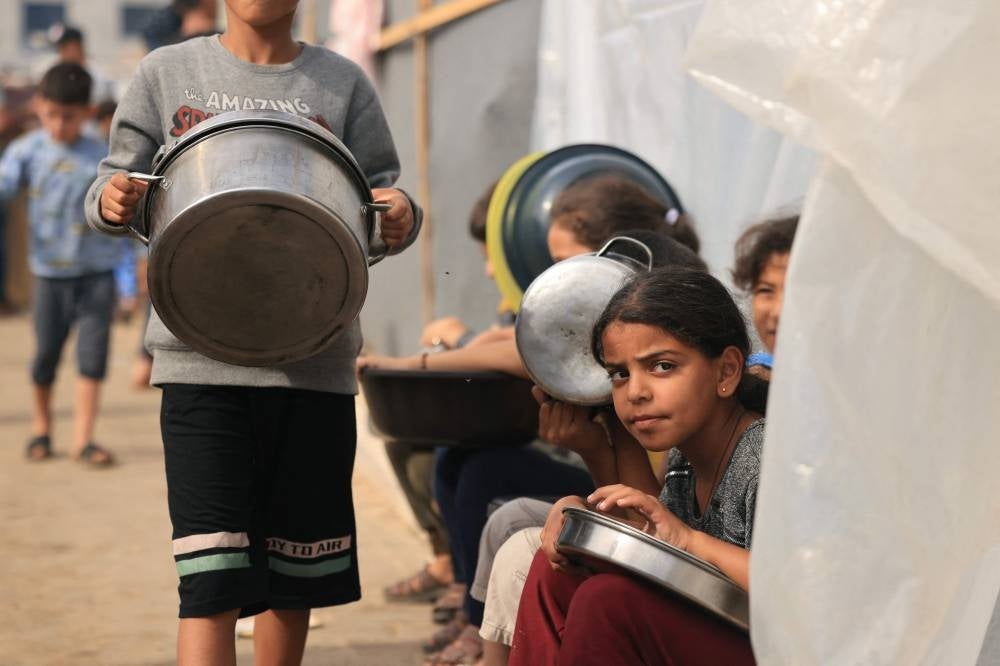 Internally displaced Palestinian children who have fled their homes in the northern Gaza Strip due to intense Israeli military bombardment, hold containers as they wait for food in Khan Yunis in the southern Gaza Strip on Nov11, 2023. (Photo by MAHMUD HAMS / AFP)