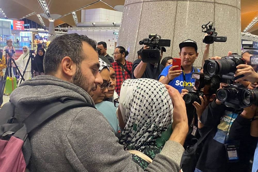 Family embraces Nurul Ain (second from right) and her husband after arriving from Palestine tonight. (SINAR PHOTO)
