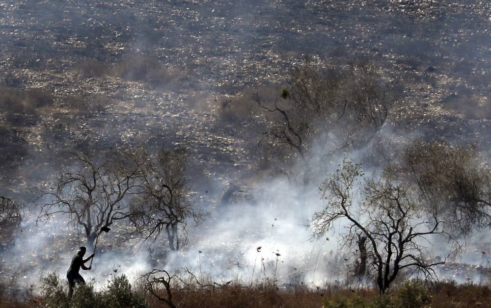 This picture taken on Oct 16, 2019 shows a Palestinian trying to extinguish a fire in an olive grove near the Palestinian village of Burin in the northern West Bank by the Israeli settlement of Yitzhar. - (Photo by Jaafar Ashtiyeh /AFP)