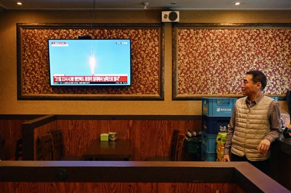 A man watches a television showing a news broadcast at a restaurant in Seoul late on Nov 21, 2023, after North Korea fired what it claims is a military spy satellite, Seoul's armed forces said on Nov 21, hours after Japan confirmed that Pyongyang had warned it of an imminent launch. - (Photo by ANTHONY WALLACE / AFP)