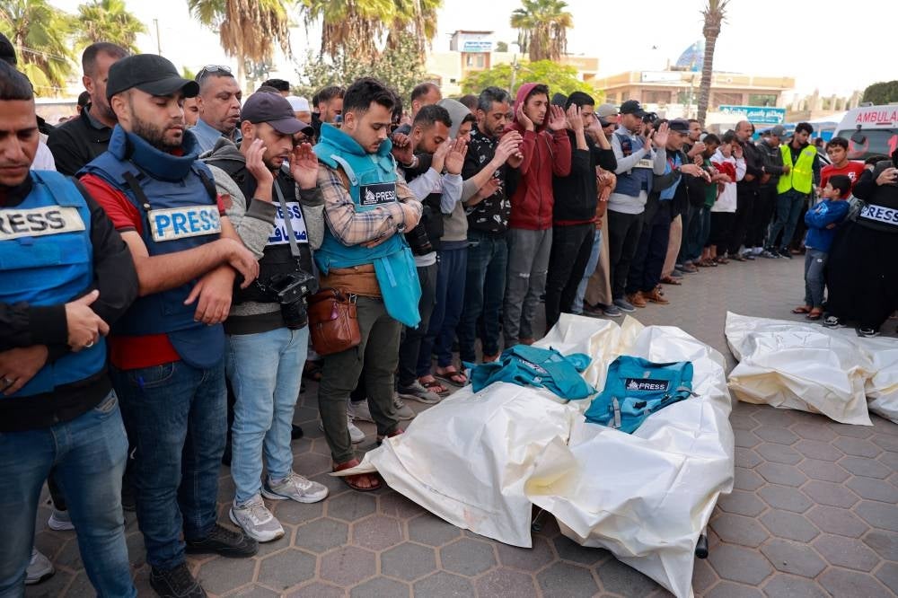 Friends and colleagues of two Palestinian journalists Hasouna Slim and Sari Mansoor, killed in an Israeli strike, pray over their bodies during their funeral in Deir al-Balah in the southern Gaza Strip on Nov 19, 2023. - (Photo by BASHAR TALEB / AFP)