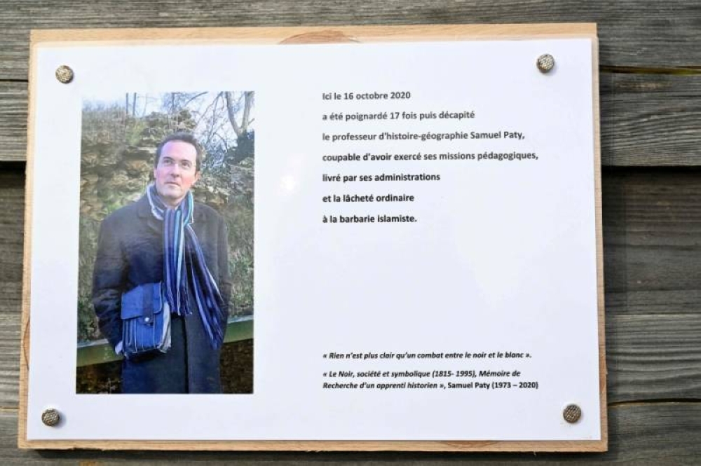 A photograph taken on Oct 16, 2023 shows a commemorative plaque for slain teacher Samuel Paty (portrait) near the Bois d'Aulne school in Conflans-Sainte-Honorine, outside Paris. - Photo by AFP