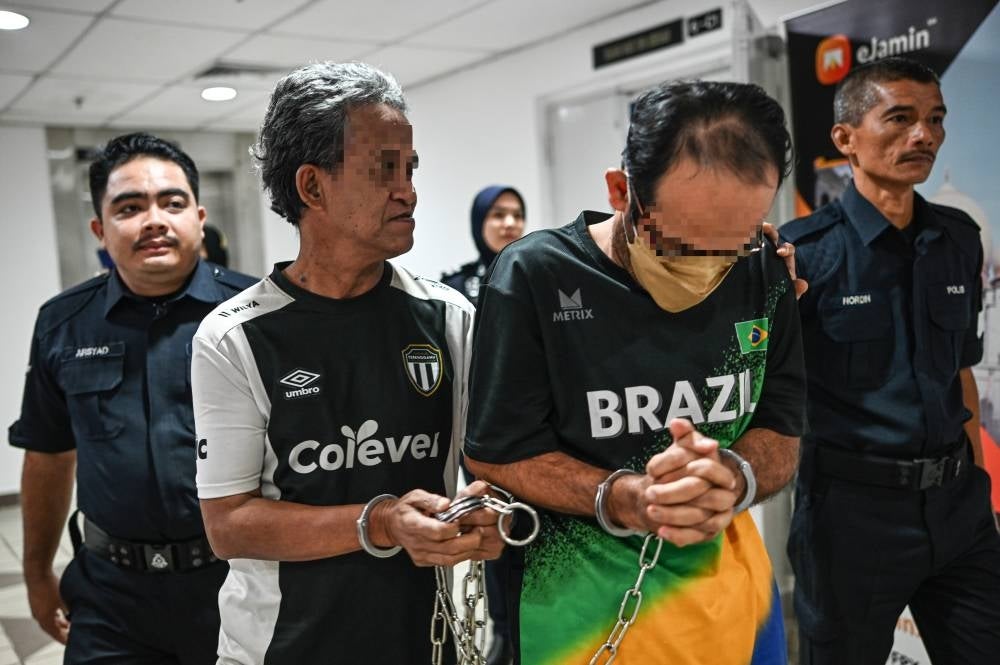 Mohammed Rashid Rahmat (second, left) pleaded not guilty to both charges before Judge Nooriah Osman. - Photo by Bernama 