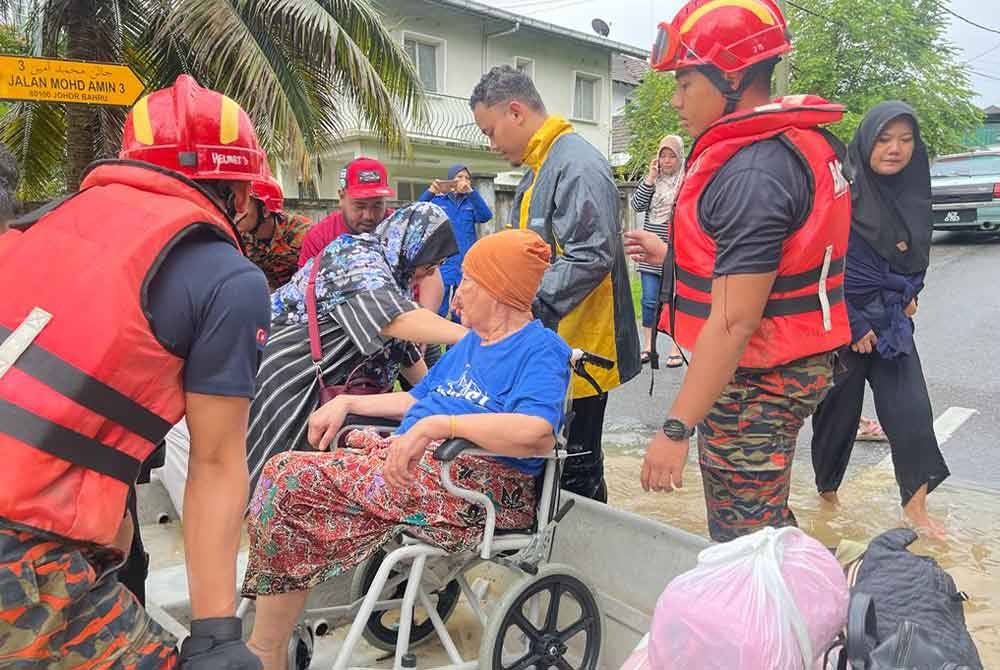 Firefighters evacuate flood victims trapped in Kampung Mohd Amin, Johor Bahru.