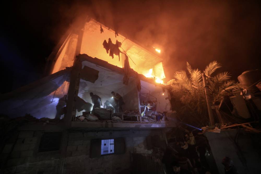 People use the lights on their telephones to search for victims amid the rubble of a smouldering building, following an Israeli strike in Rafah in the southern Gaza Strip on Dec 6, 2023. - (Photo by MAHMUD HAMS / AFP)