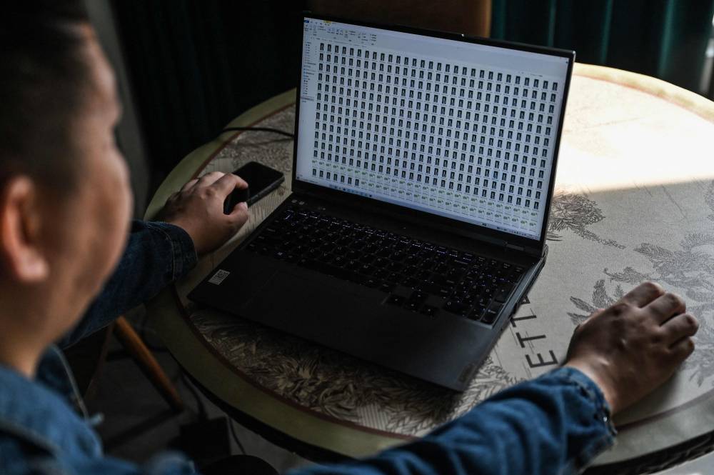 This photo taken on November 8, 2023 shows Zhang Zewei, founder of AI firm Super Brain which specialises in digital replicas of the dead, working on his laptop in Jiangyin, China's eastern Jiangsu province. - Photo by AFP