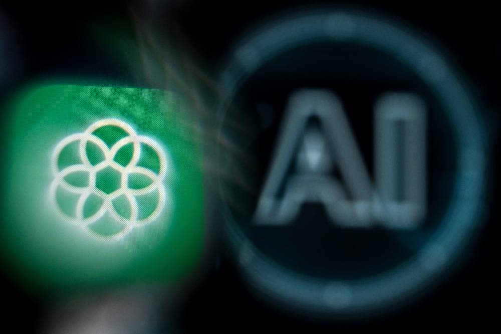 A photo taken on Nov 23, 2023 shows the logo of the ChatGPT application developed by US artificial intelligence research organisation OpenAI on a smartphone screen (L) and the letters AI on a laptop screen. - Photo by AFP