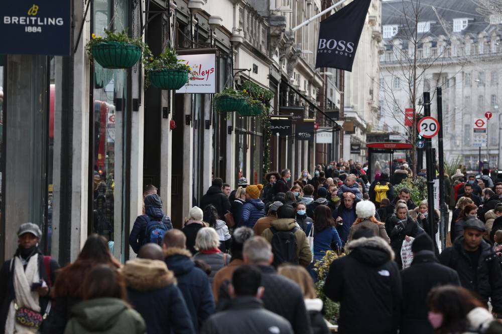 Shoppers, some wearing a facemask walk along Regent Street in London on Dec 28, 2021. - (Photo by Hollie Adams / AFP)